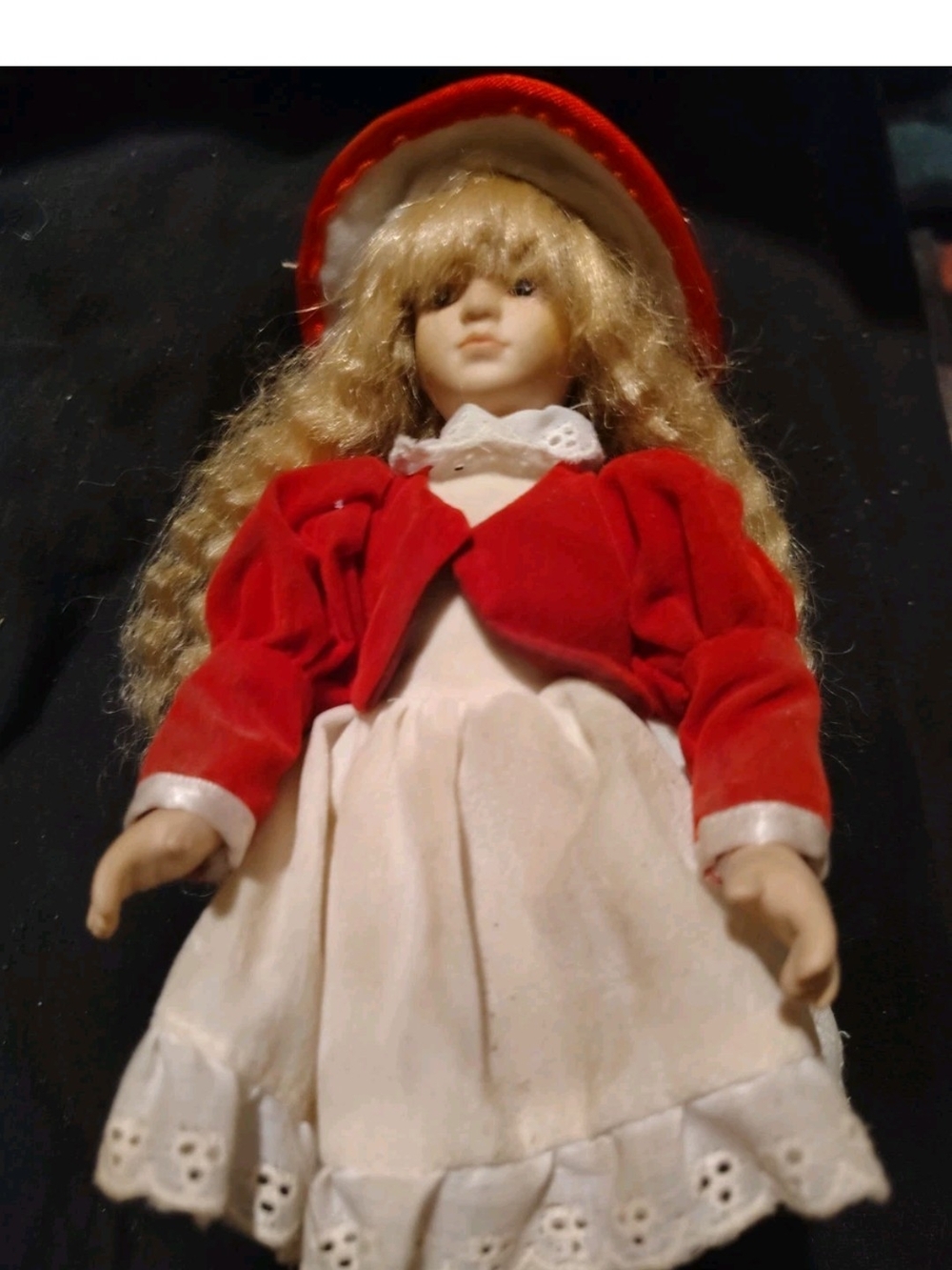 porcelain Victorian doll wearing a red velvet jacket, white lace dress